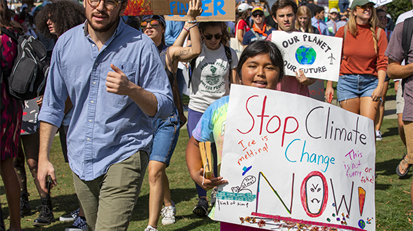 Photo of young protestor. Sign reads: Stop Climate Change Now!